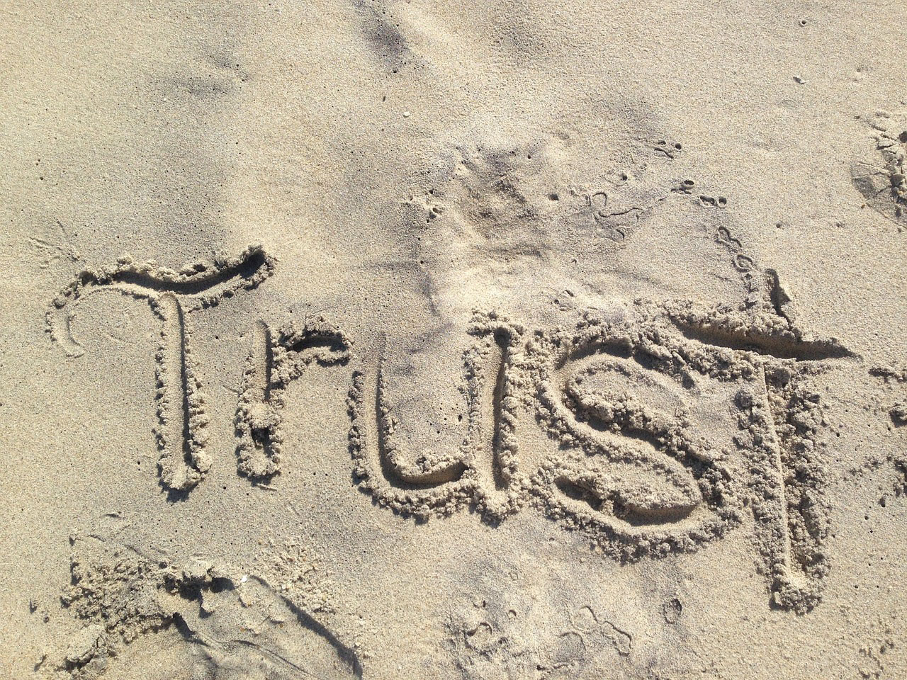 In den Sand ist das Wort 'Trust' - 'Vertrauen' geschrieben. (c) Foto: Pixabay